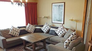 A living room with a sofa set, a coffee table, patterned rug, and a painting on the wall.
