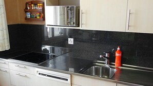 A kitchen with a black countertop, stainless steel appliances, and a dishwash unit.
