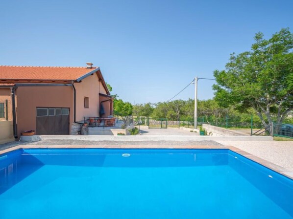 A house with a swimming pool, a patio, and a garden.
