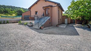 Ein zweigeschossiges Haus mit überdachter Veranda, einer Treppe und einem Schotterweg.