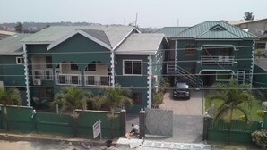 A multi-story building with a green roof and a gated entrance. - Mace Lodge (Sekondi-Takoradi)