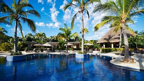 A pool surrounded by palm trees and thatched-roof structures, likely part of a resort. - Beautiful Condo in Alamar with fabulous OCEAN VIEW (La Cruz de Huanacaxtle)