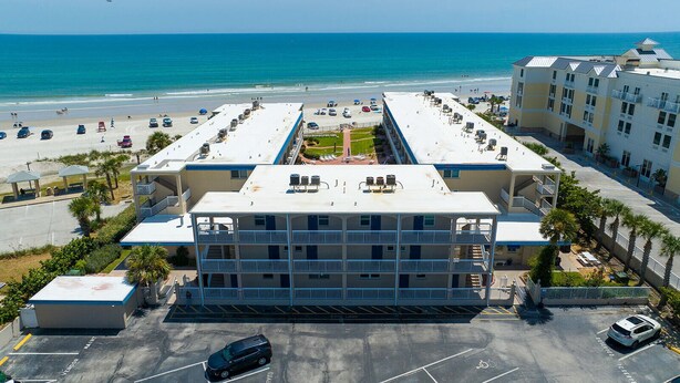 A multi-story hotel with a rooftop pool overlooking a beach.