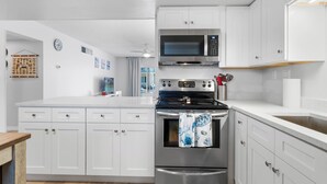 A modern kitchen with white cabinets, stainless steel appliances, and a wooden countertop.