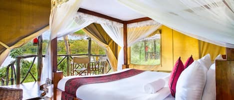 Una carpa espaciosa con una cama, una zona de comedor y vistas del paisaje circundante.