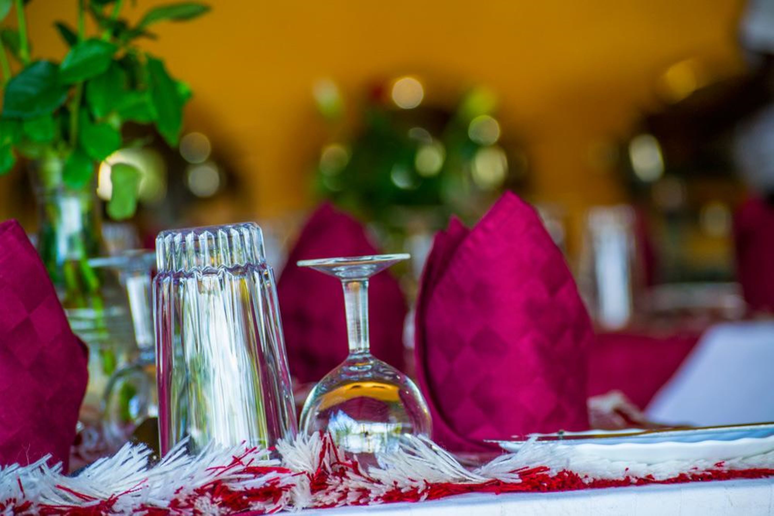 A table set with clear glassware, red napkins, and a white tablecloth.