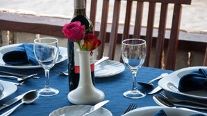 Una mesa dispuesta para comer, con una botella de vino, un florero y un mantel azul.