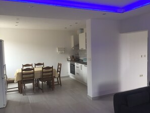 Cozy living space with a dining area and kitchenette, featuring a dining table, refrigerator, and microwave.