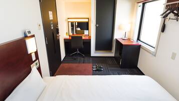 Quarto de hotel com cama, escrivaninha, cadeira, espelho, porta e janela com vista.
