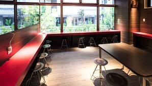 A modern bar area with a long counter, multiple stools, and large windows offering a view of the outside. - Super Hotel Tokyo Akabane-Eki Higashiguchi Ichibangai (Tokyo)