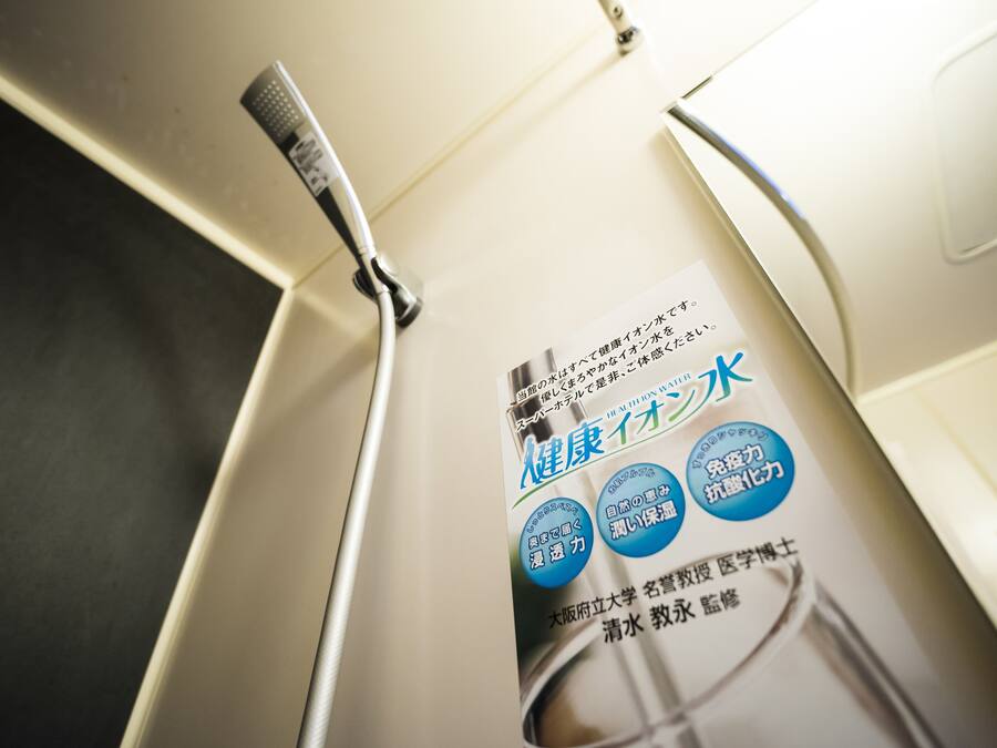 A bathroom with a shower head and a poster advertising health water.