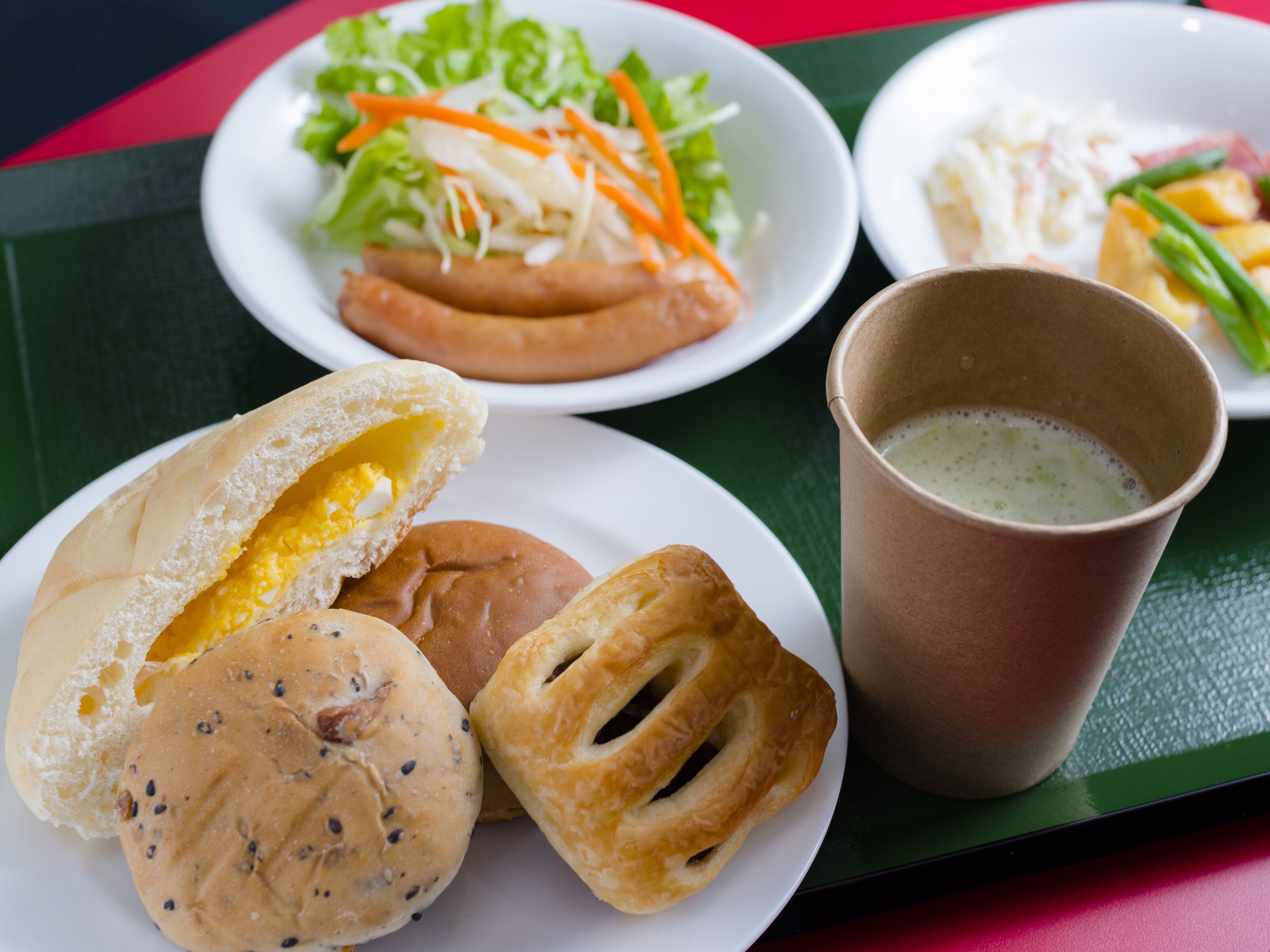 A tray with various food items including buns, a cup of coffee, and plates with salads and vegetables.