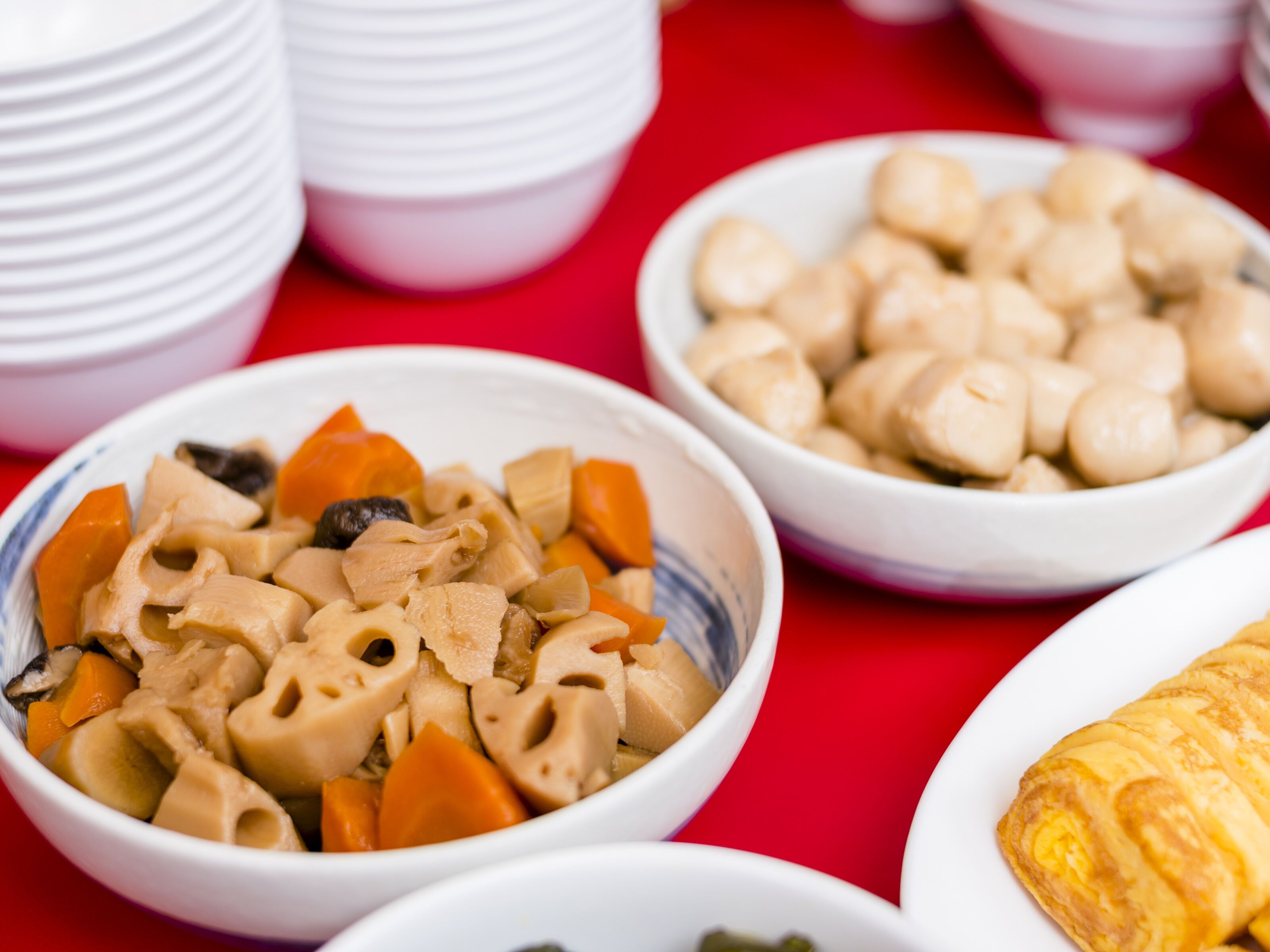 Ein Tisch mit verschiedenen Speisen, darunter Pasta, Gemüse und einem Gebäck.