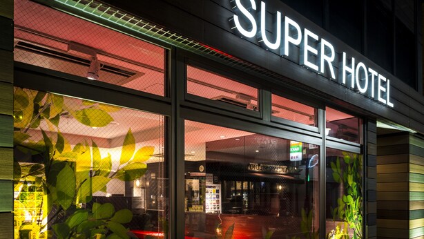 The exterior of the Super Hotel with large windows and a visible interior bar area. - Super Hotel Tokyo Akabane-Eki Higashiguchi Ichibangai (Tokyo)