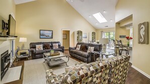 A spacious living room with a fireplace, two sofas, a coffee table, and a patterned armchair.