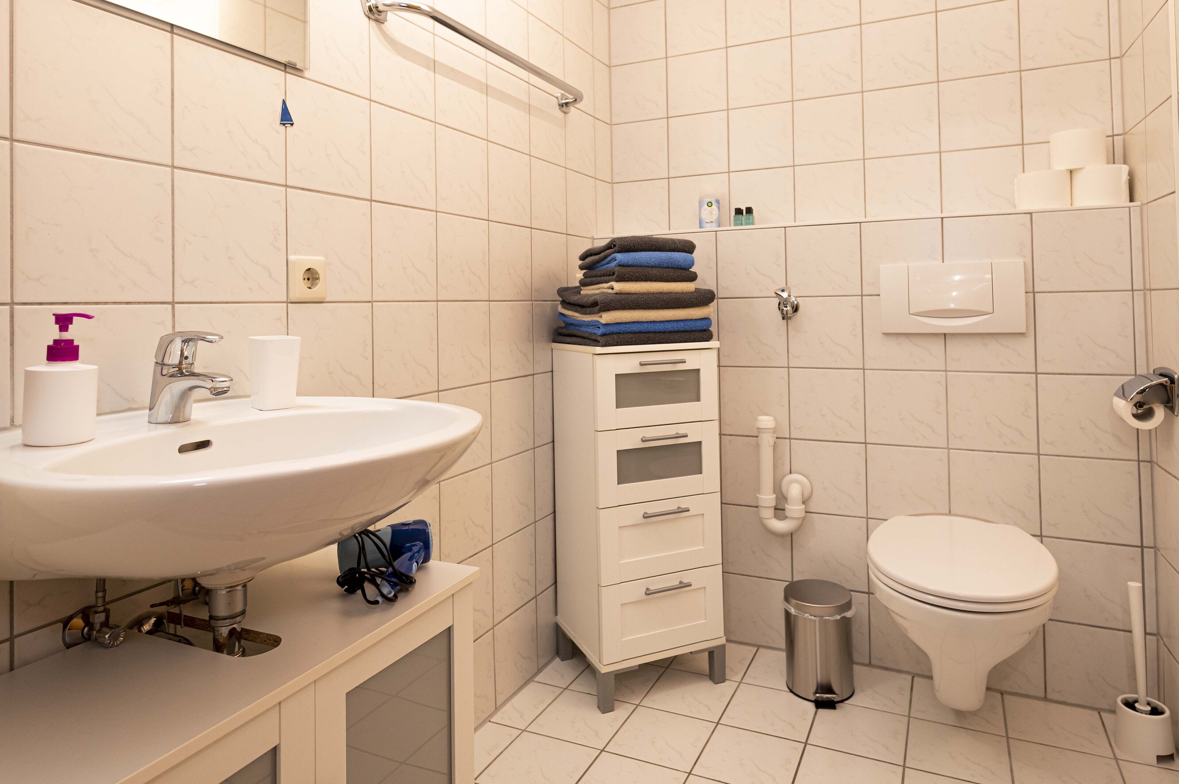 Et moderne badeværelse med vask, toilet og skab.