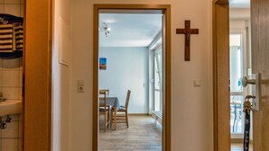 A hallway with wooden flooring, a dining area with a table and chairs, and a cross on the wall. - Ferienwohnungen beim Europapark Rust (Rust)