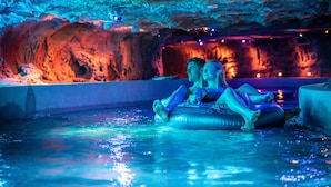 A couple relaxing in a hot tub with a cave-like interior and ambient lighting. - Ferienwohnungen beim Europapark Rust (Rust)