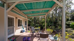 Eine überdachte Terrasse im Freien mit Sitzgelegenheiten, einem Grill und Trainingsmatten.