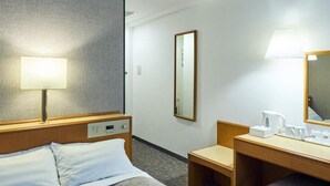 A hotel room with a bed, bedside table, lamp, mirror, and a small desk with a chair. - Hotel Lexton Kagoshima Annex (Kagoshima)