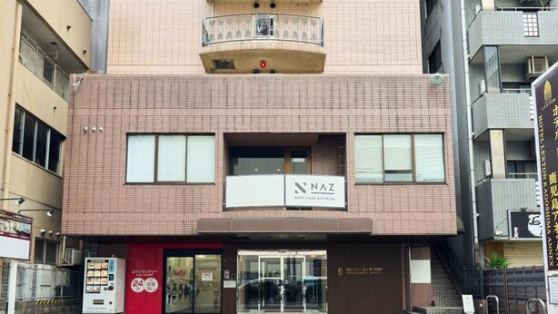 A multi-story building with a ground-level entrance, a visible sign for a fitness center, and a clear view of the entrance area. - Hotel Lexton Kagoshima Annex (Kagoshima)