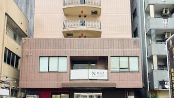 Um edifício de vários andares com entrada no andar térreo, uma placa indicando um centro de cuidados corporais e fitness, e um hidrante visível.