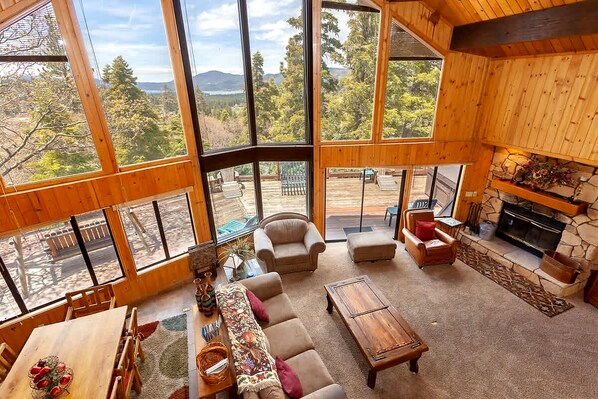 Un salón amplio con ventanas grandes, una chimenea y vistas al exterior.