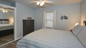 A bedroom with a bed, a dresser, a mirror, a ceiling fan, and a window with curtains. - 3rd and Surf- 2 blocks from the lake, 1 block from the Legendary Surf Ballroom (Clear Lake)