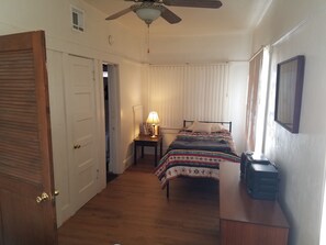 Cozy retreat with a single bed, ceiling fan, and desk with a printer.