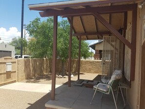 Relax in a serene outdoor space with a pergola overhead, two comfortable chairs, and a peaceful atmosphere.
