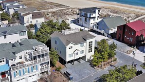 A coastal residential area with houses, a beach, and a clear view of the ocean. - The Sand Trap in South Bethany: Steps from the ocean!  Hot Tub! Captain's walk! (Bethany Beach)