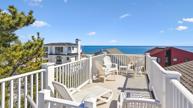 A coastal property with a deck overlooking the ocean, featuring outdoor seating and a view of the sea. - The Sand Trap in South Bethany: Steps from the ocean!  Hot Tub! Captain's walk! (Bethany Beach)