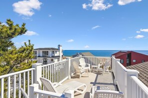 Propiedad costera con terraza que da al océano, con mobiliario exterior y vista al mar.