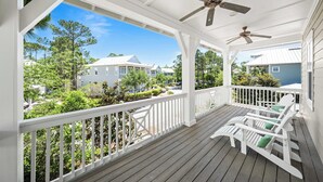 A covered porch with white railings and two rocking chairs with green cushions. - Exquisite 4-Bedroom WaterColor Retreat with Bikes, Golf Cart, and Pet-Friendly Amenities! (Santa Rosa Beach, Florida)