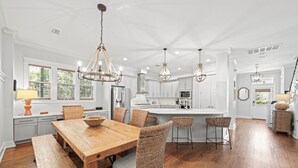 A spacious kitchen with a wooden dining table, wicker chairs, and pendant lighting. - Exquisite 4-Bedroom WaterColor Retreat with Bikes, Golf Cart, and Pet-Friendly Amenities! (Santa Rosa Beach, Florida)