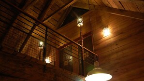 Un intérieur en bois avec un plafond haut, des poutres apparentes et des luminaires suspendus.