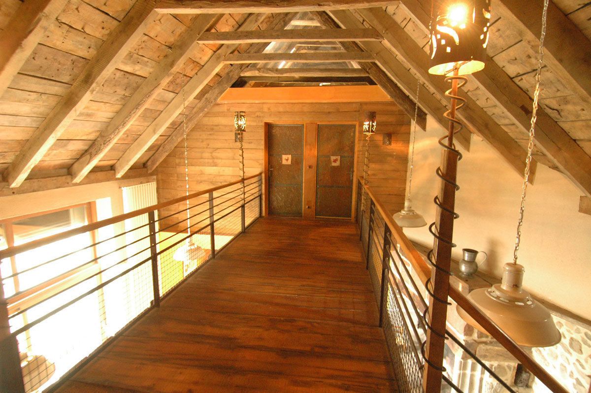 A wooden interior with a high ceiling, a wooden staircase, and two doors.