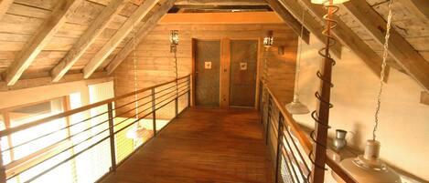 A wooden interior with a high ceiling, a wooden staircase, and two doors.
