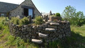 Une construction en pierre dotée d’un toit triangulaire, d’une porte et d’un mur en pierre sur lequel s’élève un escalier.