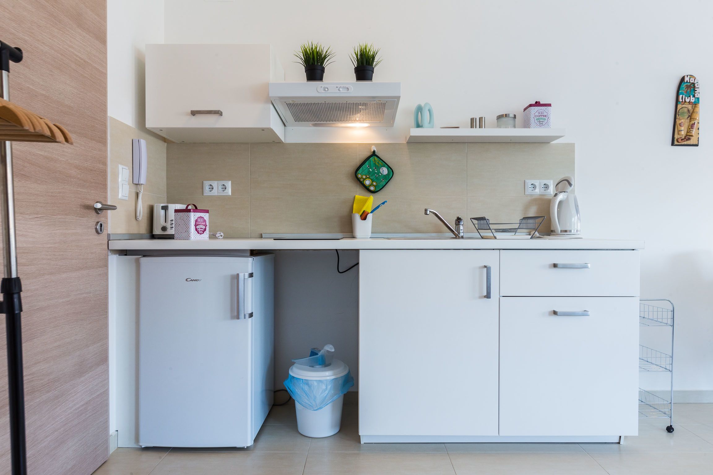 A compact kitchen with a refrigerator, a sink, and a countertop with various items.