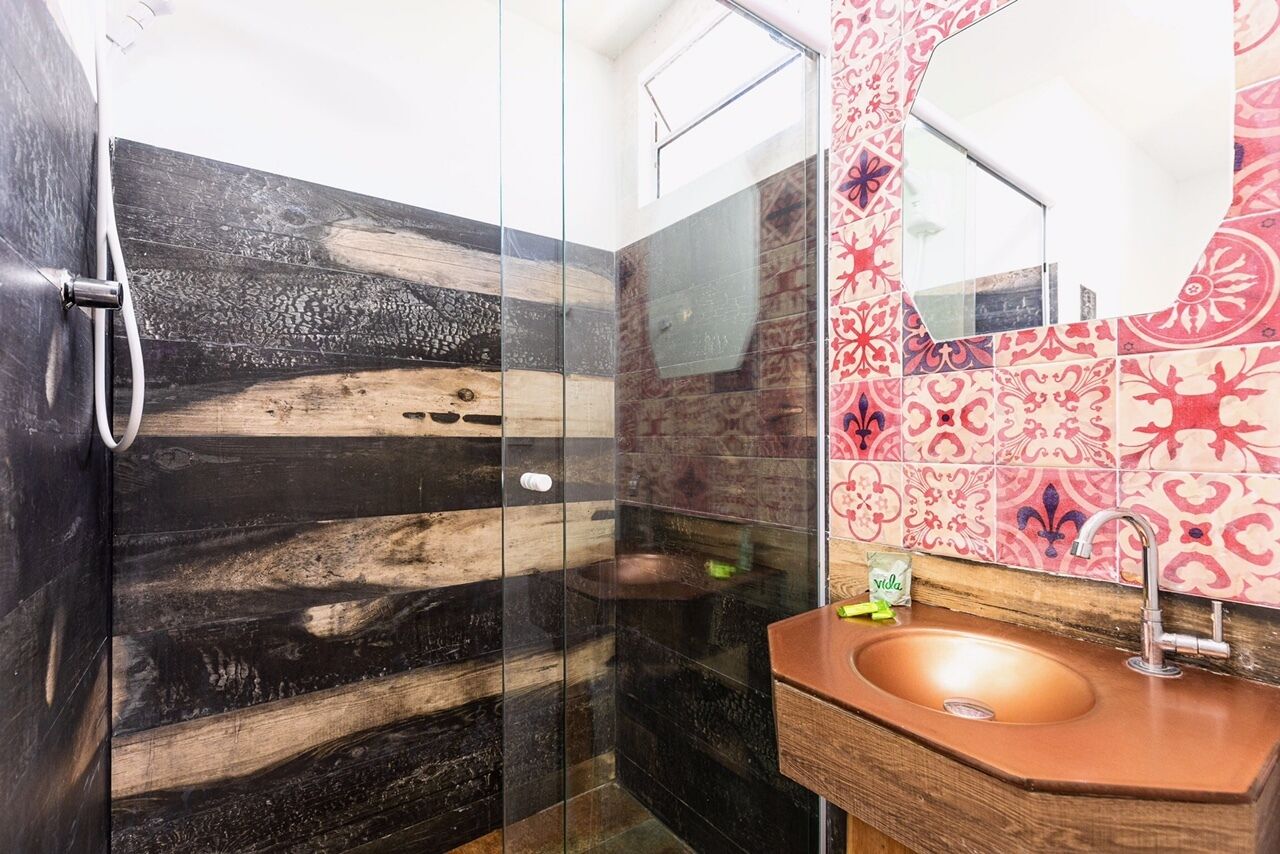 Un bagno con box doccia in vetro, mobile bagno in legno e lavandino con specchio.