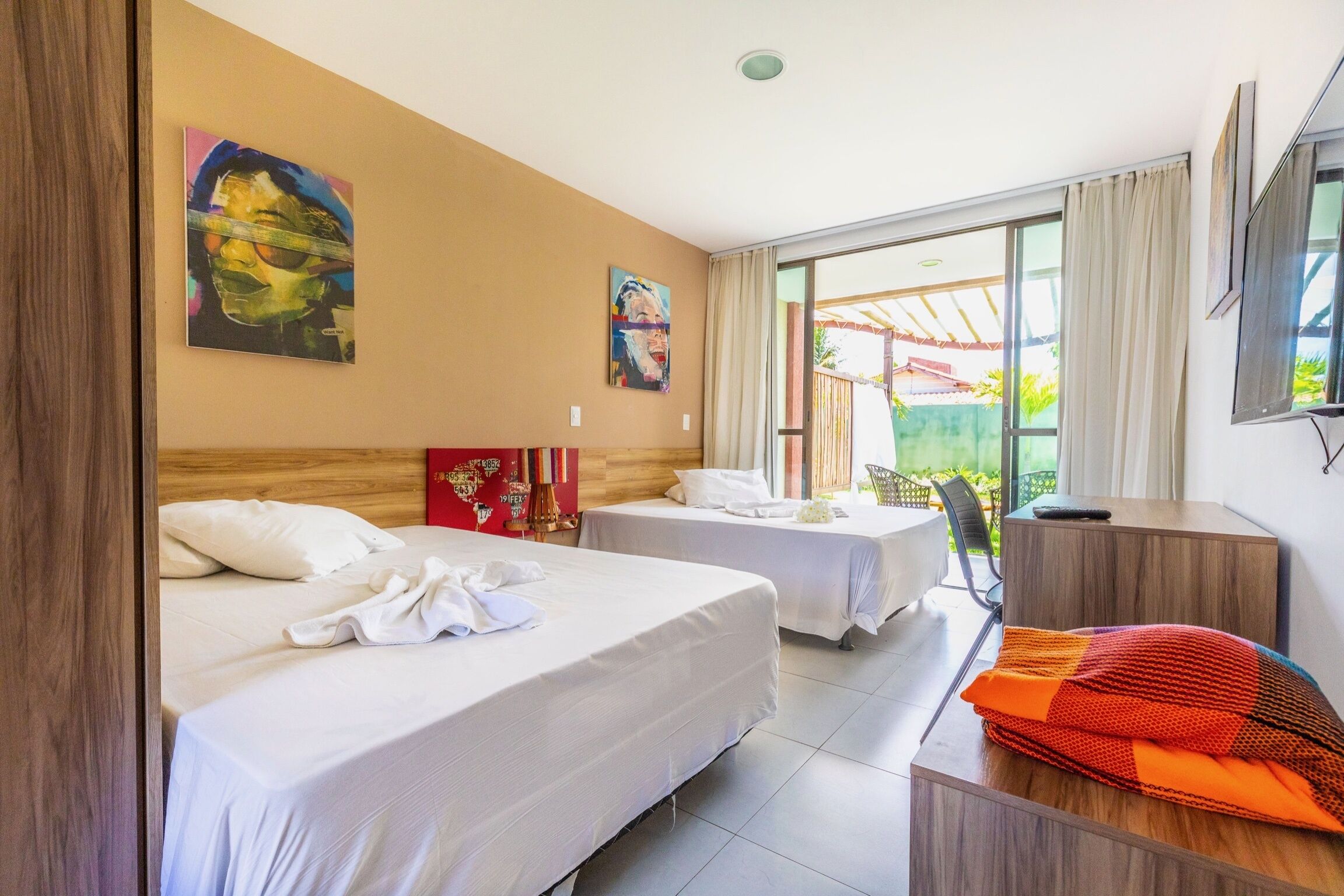 A hotel room with two beds, a desk, and a large window.