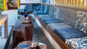 A cozy lounge area with a long sofa, wooden coffee tables, and a mural on the wall. - Xainã Pousada de Charme (Caucaia)
