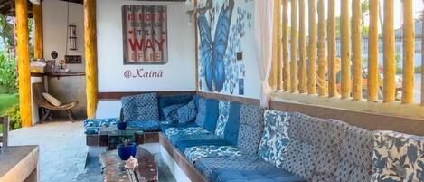 Un rincón de sala acogedor con un sofá amplio, mesas de centro de madera y un mural en la pared.