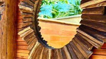 A wooden wall with a circular mirror reflecting greenery.