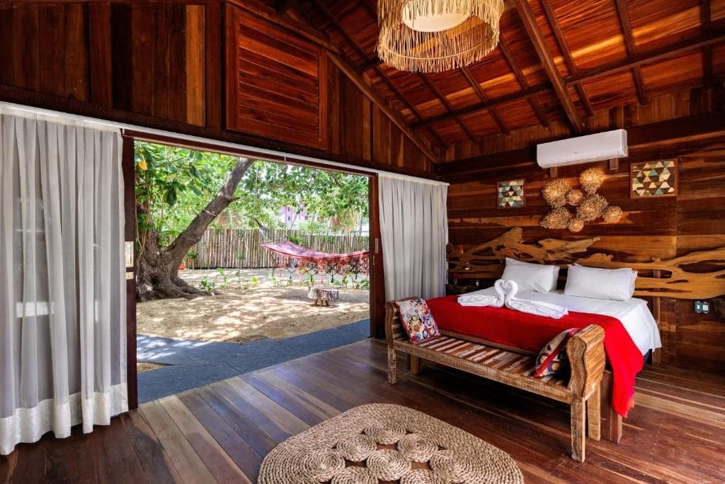 Una habitación de madera con una cama, un tapete tejido para el suelo y vistas a un jardín.