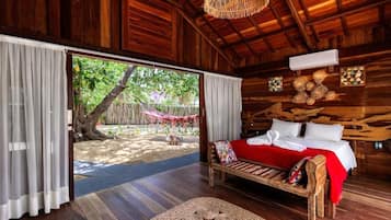 Una habitación de madera con una cama, un tapete tejido para el suelo y vistas a un jardín.