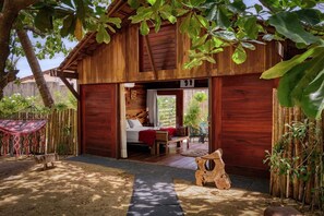 A wooden cabin with a bed, a small table, and a bench. - Xainã Pousada de Charme (Caucaia)