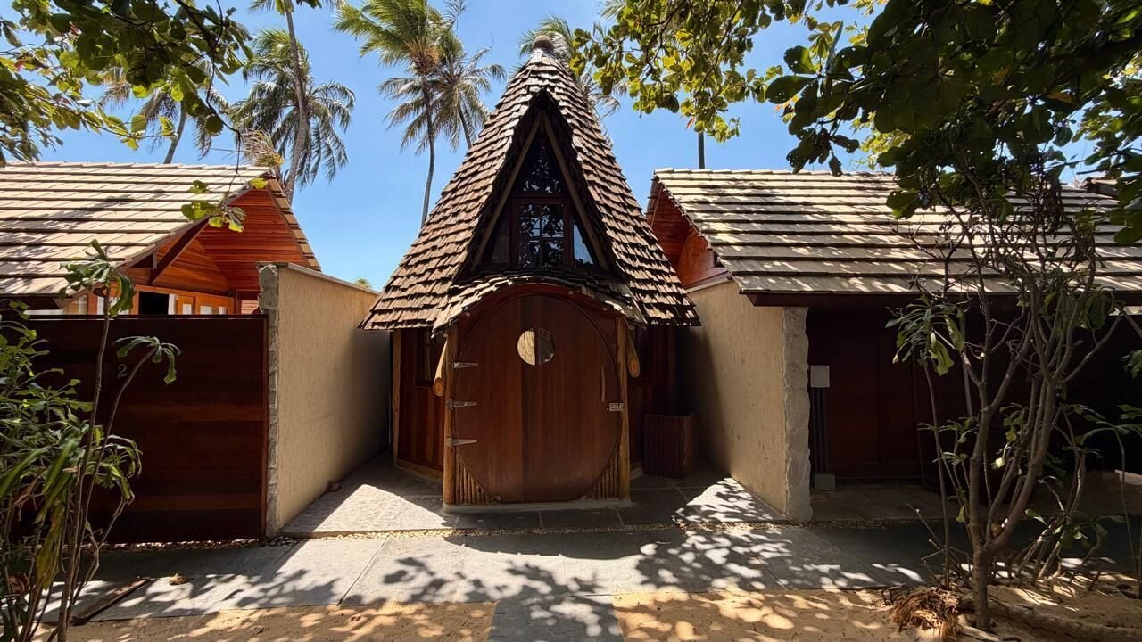 A traditional wooden building with a peaked roof, a central door, and a small porch area.