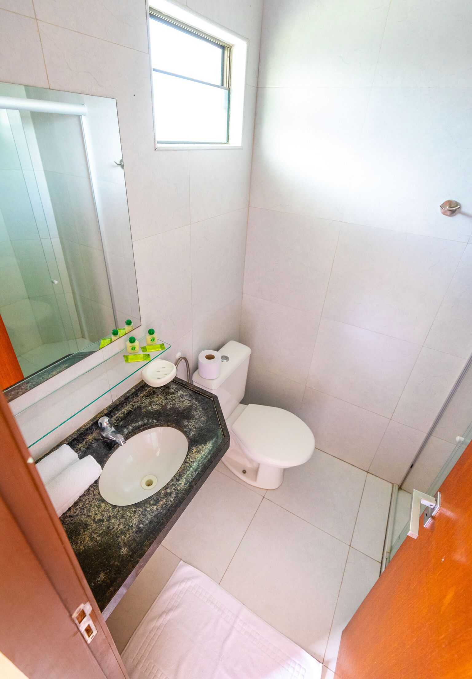 Een badkamer met een wastafel, spiegel, toilet en een klein raam.